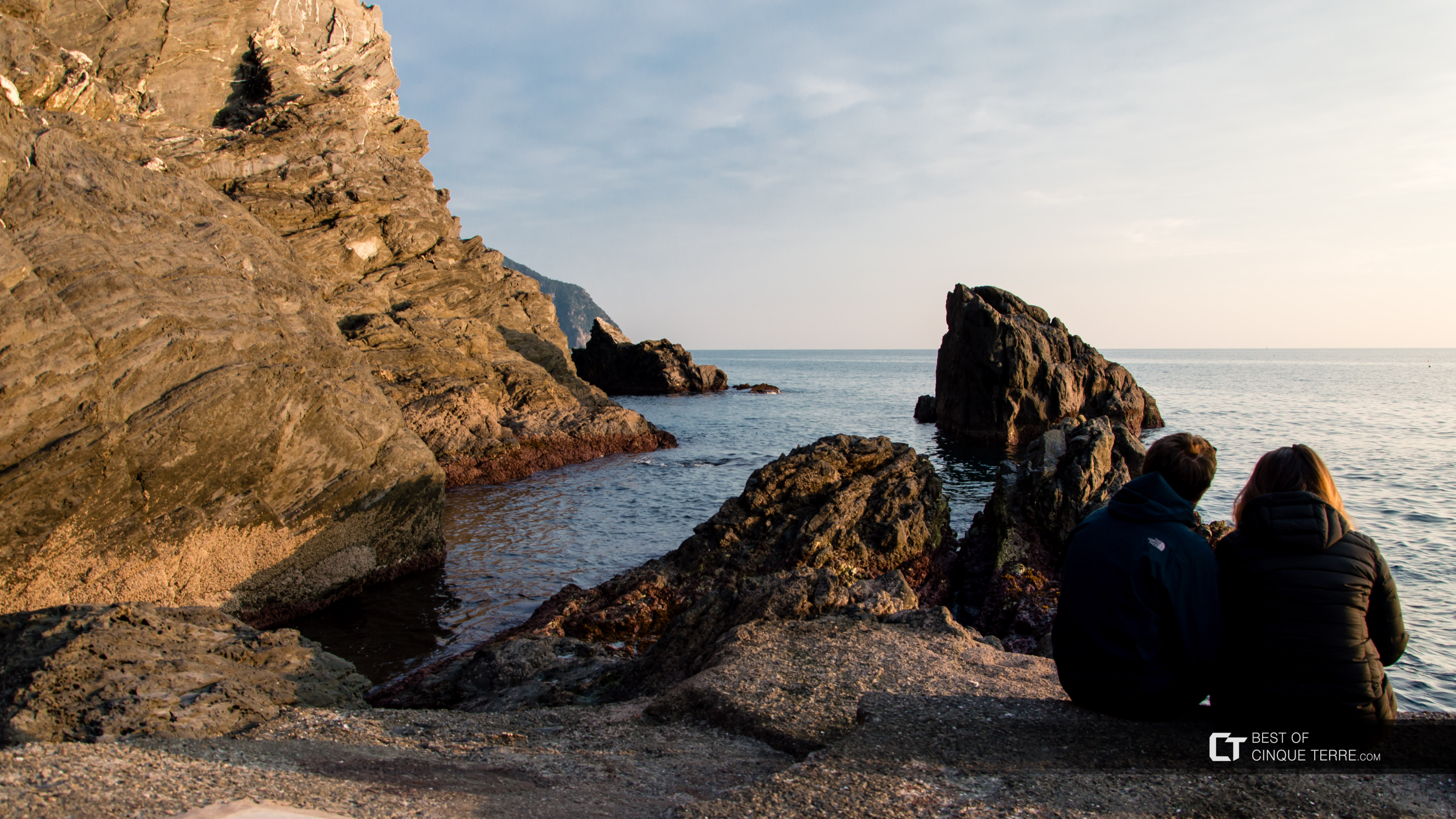 Odpoczynek na skałach obok przystani zimą, Manarola, Cinque Terre, Włochy